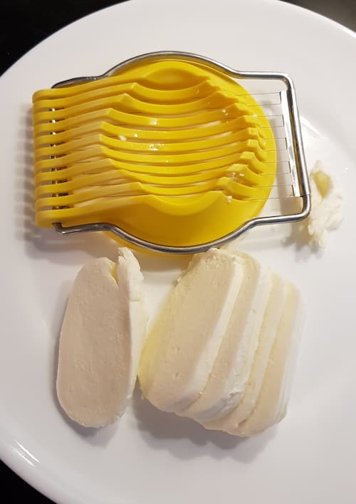 Mozzarella mit dem Eierschneider in Scheiben geschnitten.